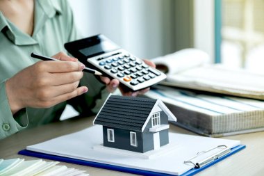 Calculating home finances with calculator and house model.