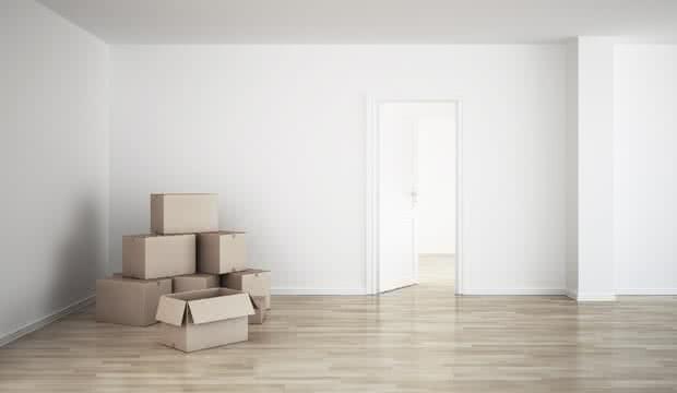 Empty room with moving boxes on a wooden floor.