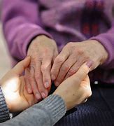 Elderly hands comforted by younger hands, symbolising compassion and caregiving.