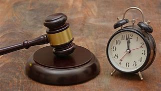 Gavel and clock on wooden table, symbolising justice and time.