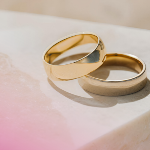 Two gold wedding bands on a marble surface, elegant and classic design.