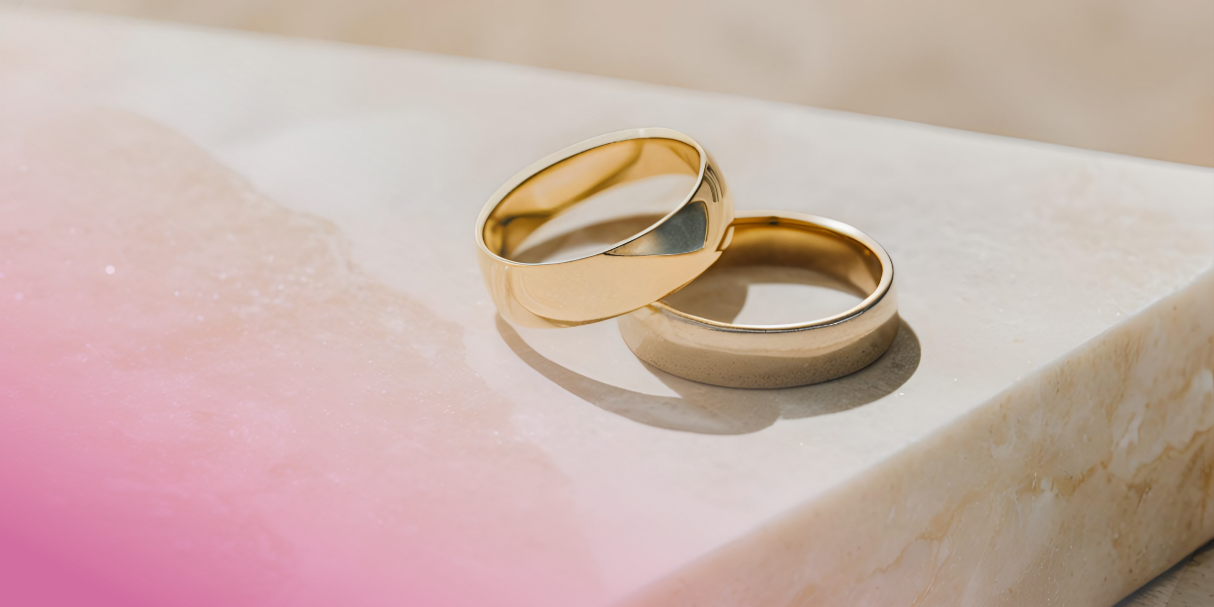 Two gold wedding bands on a marble surface, elegant and classic design.