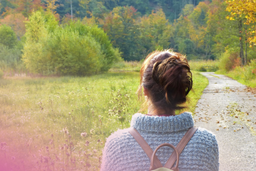 Woman in a jumper walking along a forest path in autumn.