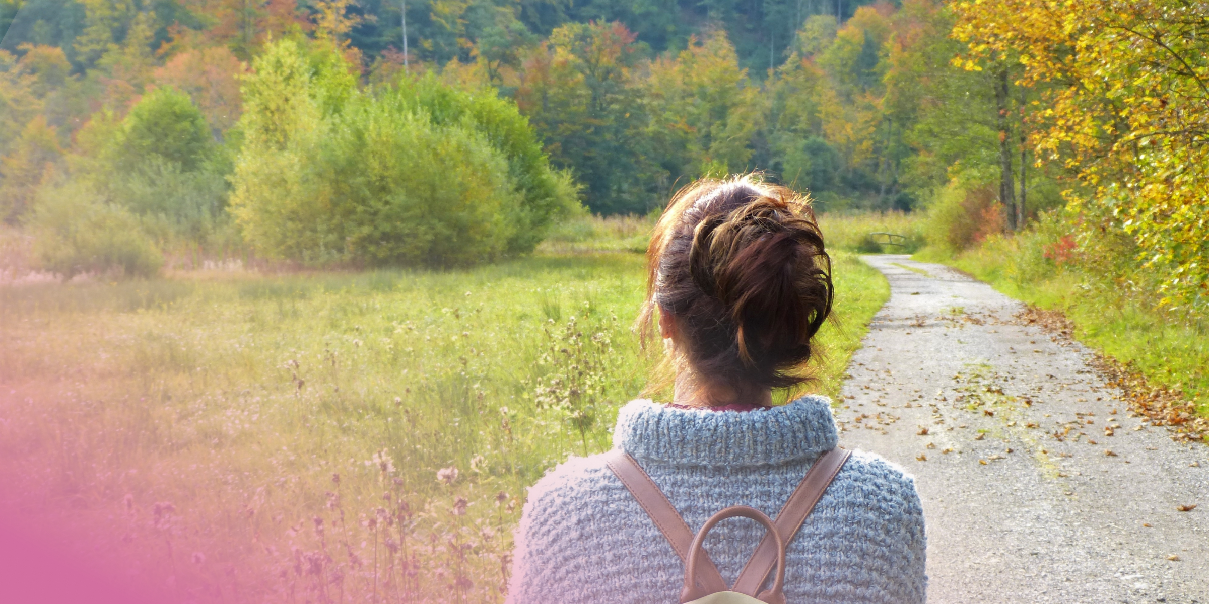Woman in a jumper walking along a forest path in autumn.