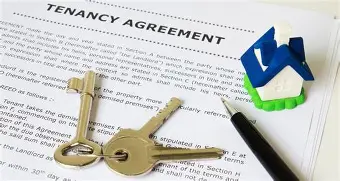 Tenancy agreement with keys, pen, and small house model.
