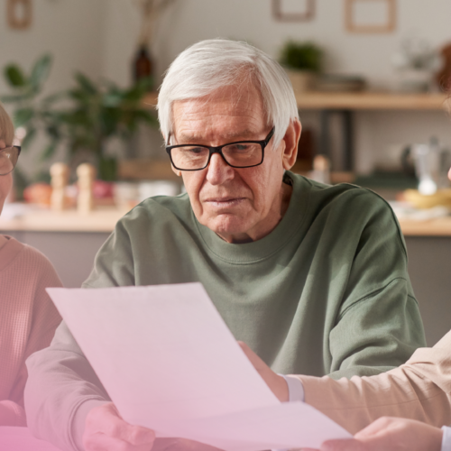 Elderly couple reviewing documents with a consultant in a cosy home setting.