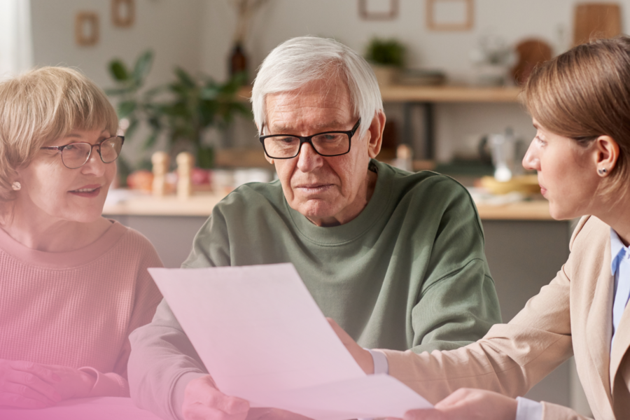 Elderly couple reviewing documents with a consultant in a cosy home setting.