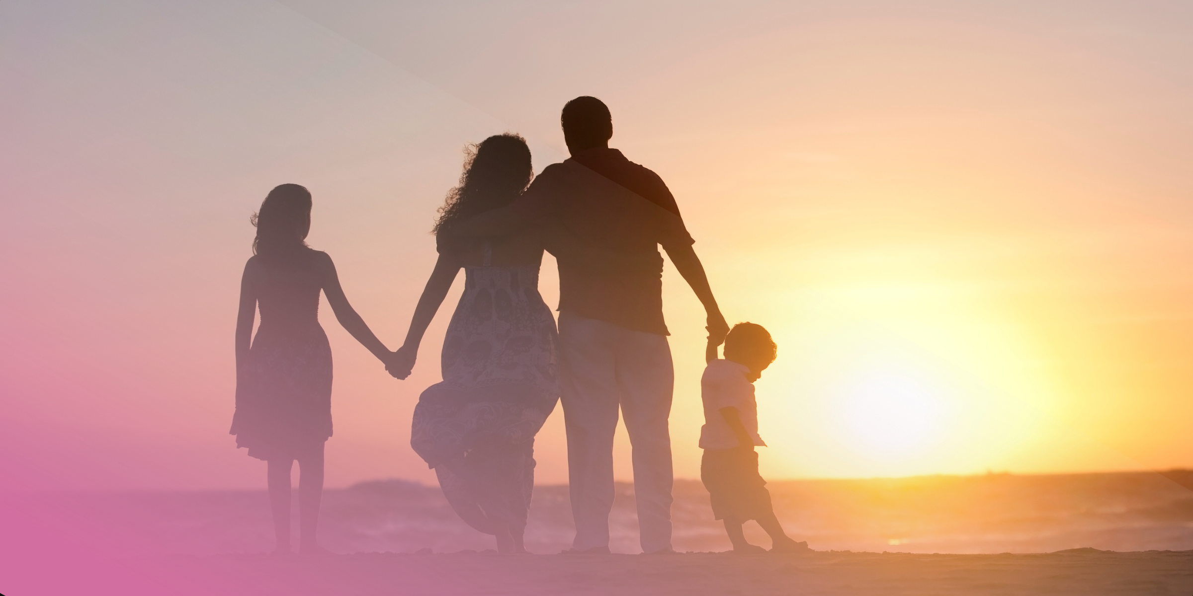 Family enjoying a beach sunset, holding hands with pink sky and warm glow.