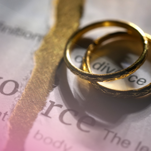 Two gold rings on a torn divorce document background.