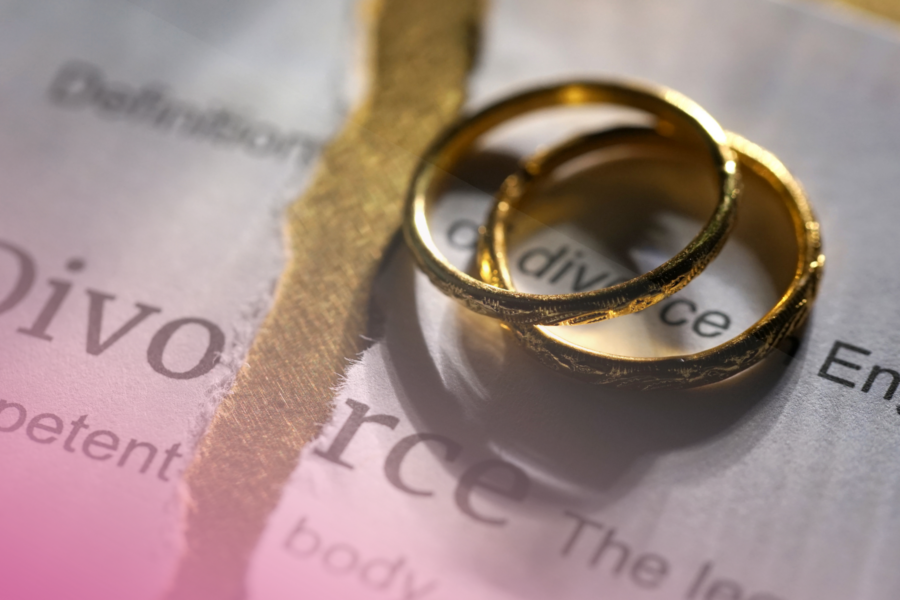 Two gold rings on a torn divorce document background.
