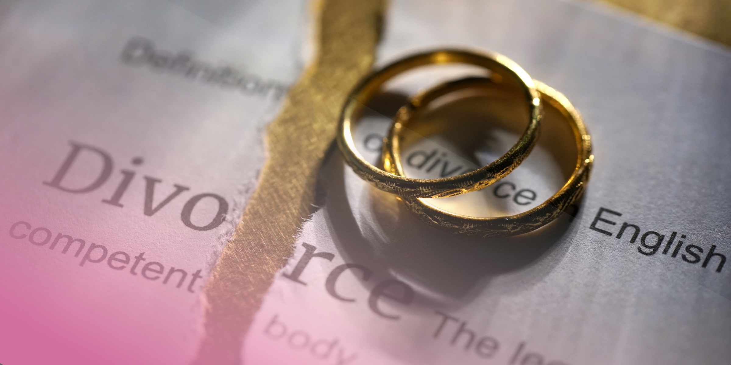 Two gold rings on a torn divorce document background.