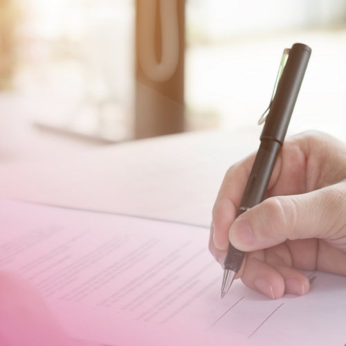Close-up of a hand signing a contract on a clipboard with a pen.