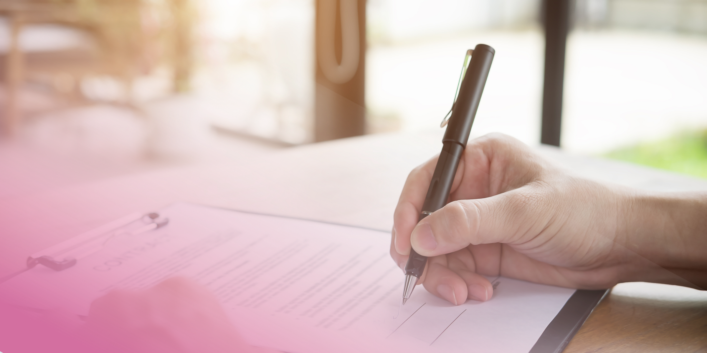 Close-up of a hand signing a contract on a clipboard with a pen.