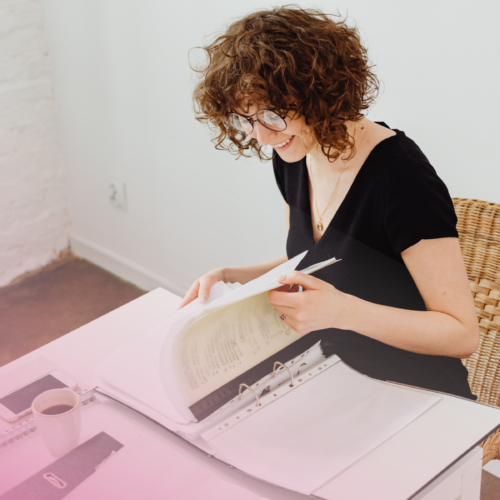 Person reading documents at desk with coffee cup.