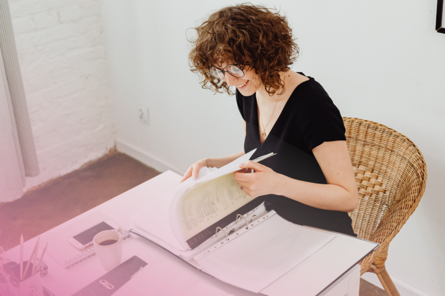 Person reading documents at desk with coffee cup.