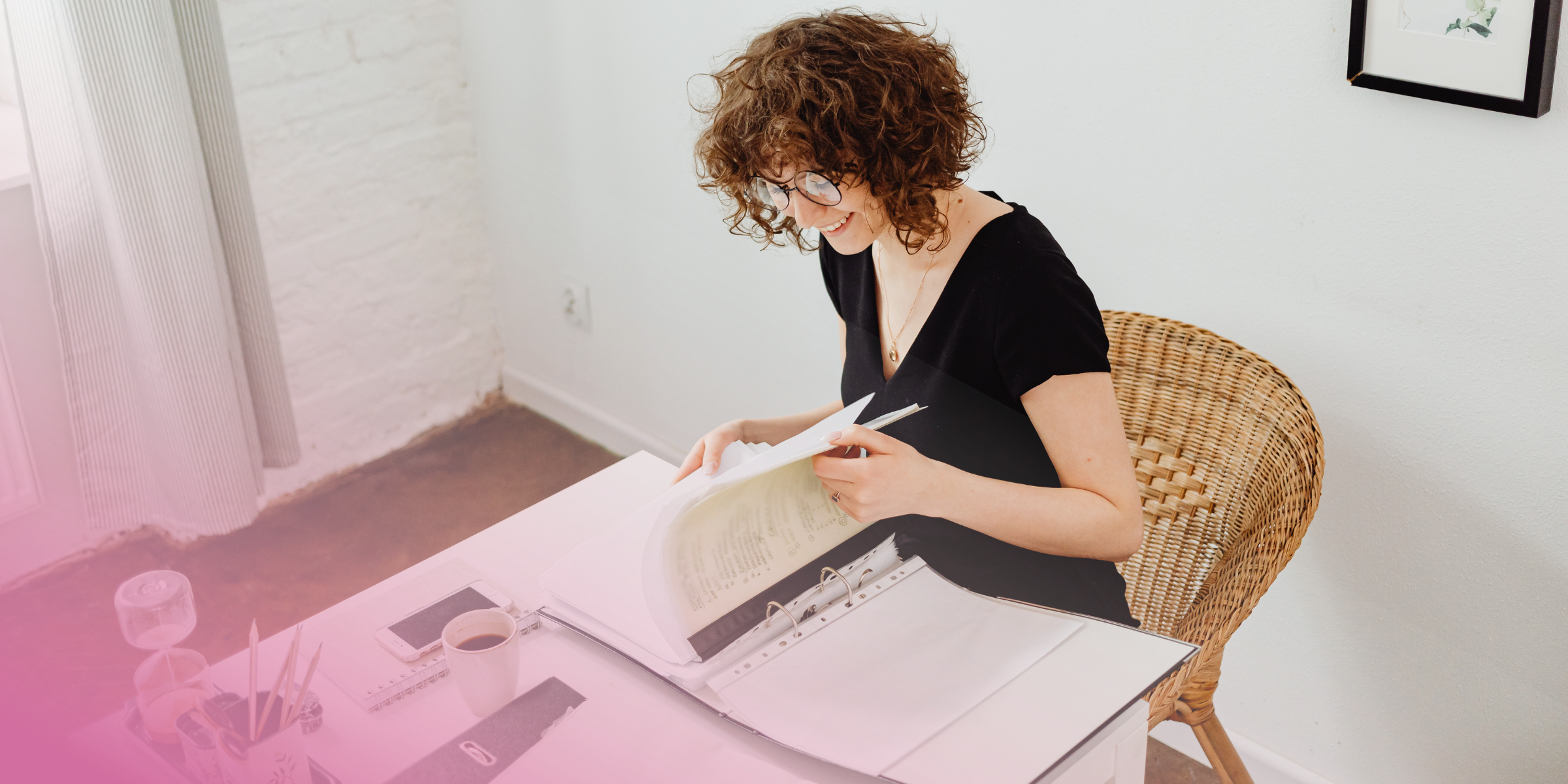 Person reading documents at desk with coffee cup.