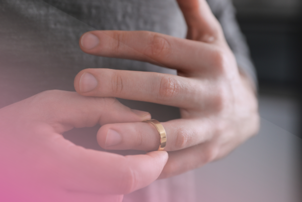 Person removing a gold wedding ring from finger.