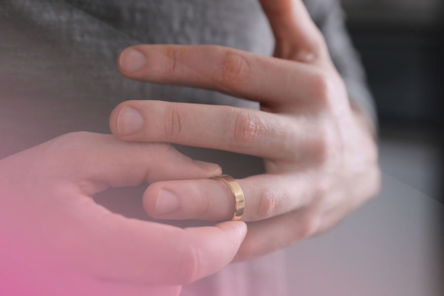 Person removing a gold wedding ring from finger.