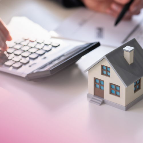 House model, calculator, and paperwork on a desk, symbolising mortgage calculations.