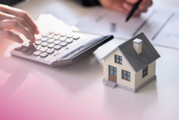 House model, calculator, and paperwork on a desk, symbolising mortgage calculations.