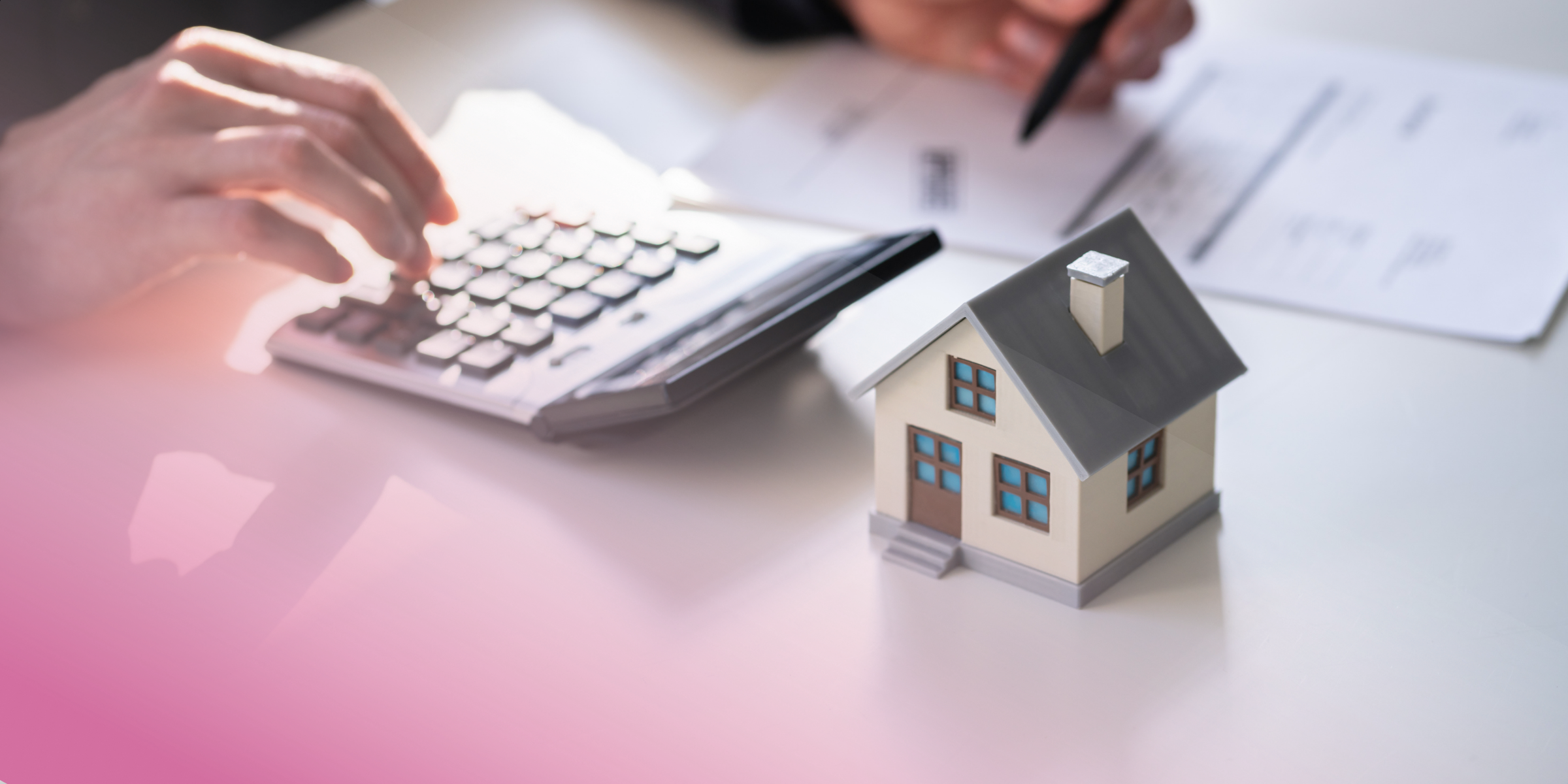 House model, calculator, and paperwork on a desk, symbolising mortgage calculations.