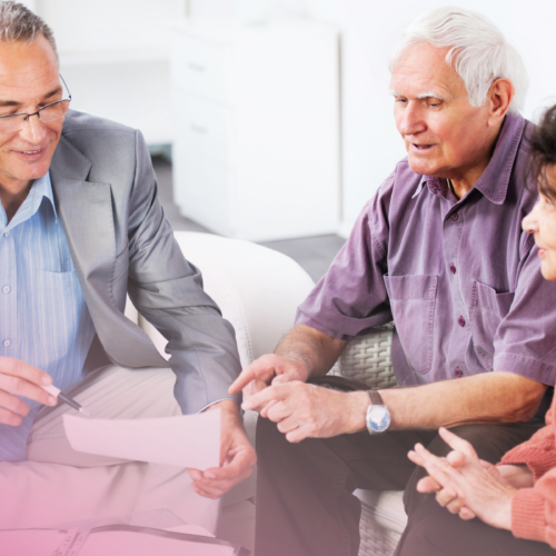Elderly couple in discussion with advisor, reviewing documents on sofa.