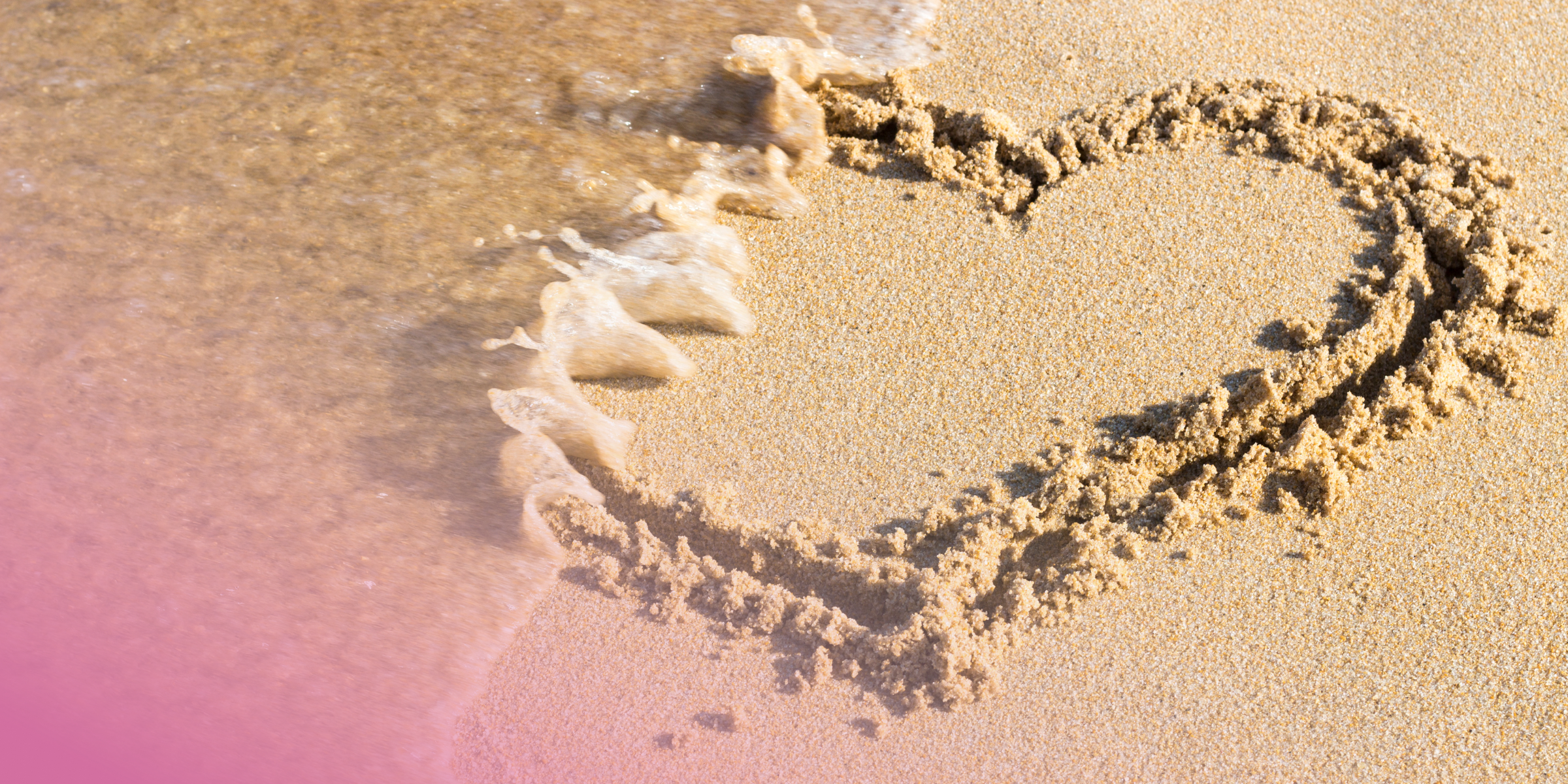 Heart shape drawn in sand as a wave washes over, symbolising fleeting moments by the seaside.