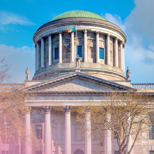 Historic courthouse with domed roof and columns under blue sky.